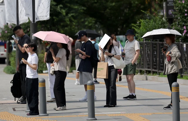 23일 서울 광화문광장에서 시민들이 양산을 쓴 채 걸어가고 있다. 연합뉴스